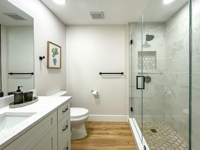 bathroom featuring hardwood / wood-style floors, a shower with shower door, toilet, and vanity