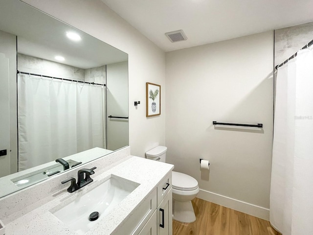 bathroom with hardwood / wood-style floors, a shower with curtain, toilet, and vanity