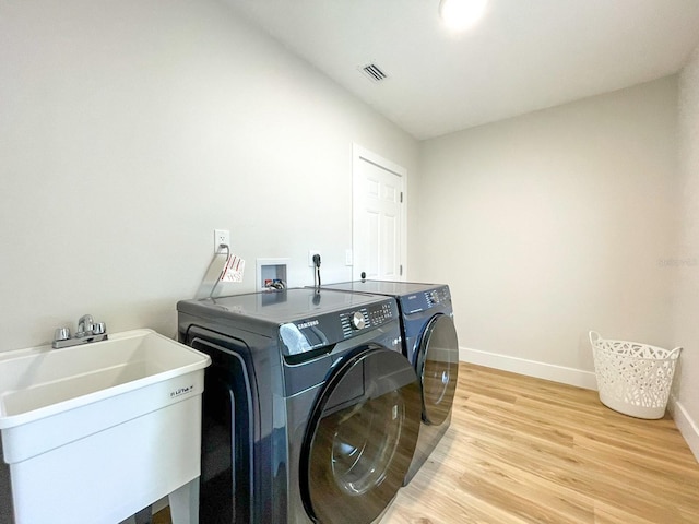 washroom featuring sink, independent washer and dryer, and light hardwood / wood-style flooring