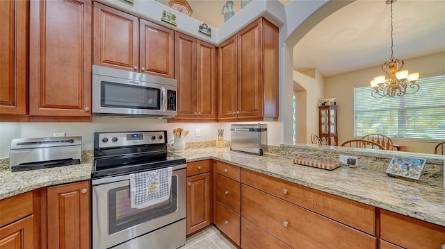 kitchen with a notable chandelier, light tile patterned floors, appliances with stainless steel finishes, hanging light fixtures, and light stone counters