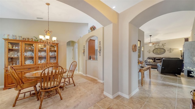 carpeted dining area with ceiling fan with notable chandelier and lofted ceiling