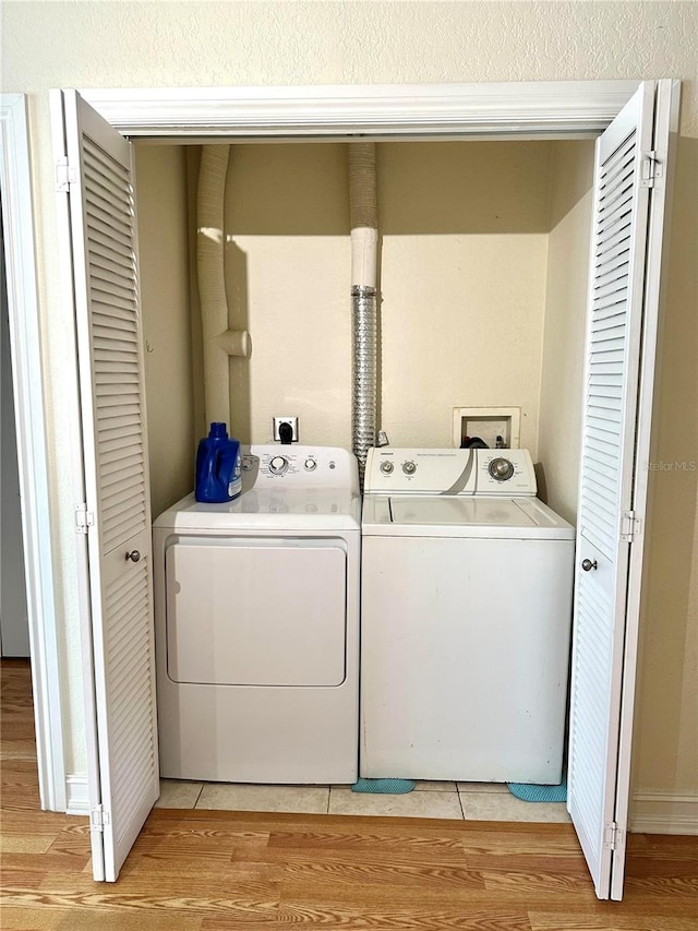 clothes washing area featuring light hardwood / wood-style flooring and washing machine and clothes dryer