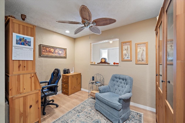 office area with light hardwood / wood-style floors, ceiling fan, and a textured ceiling