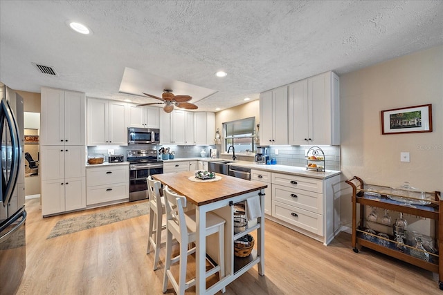 kitchen with ceiling fan, light hardwood / wood-style flooring, stainless steel appliances, and white cabinets