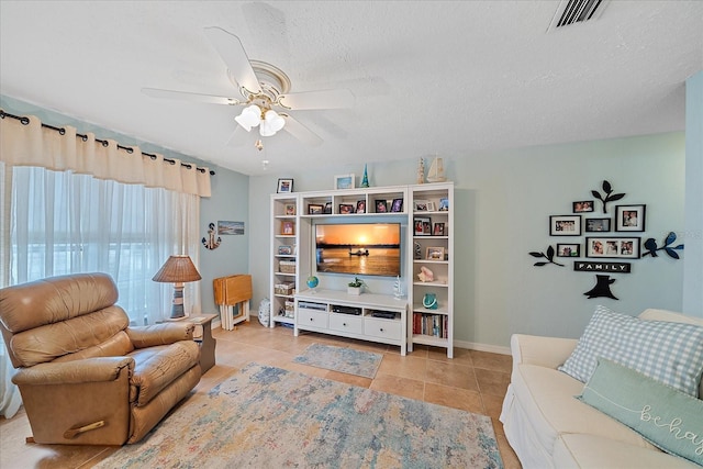 living room with ceiling fan, a textured ceiling, and light tile patterned floors