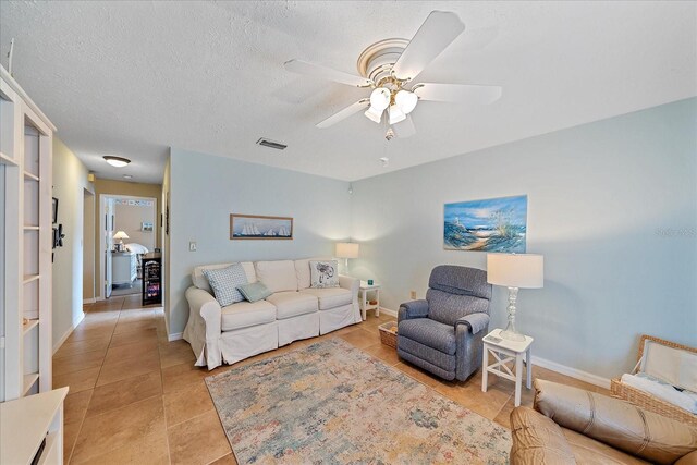 tiled living room with a textured ceiling and ceiling fan