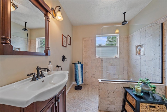 bathroom with a tile shower, a textured ceiling, and vanity