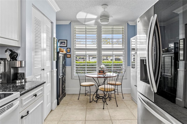 kitchen featuring a textured ceiling, ceiling fan, ornamental molding, and white cabinetry