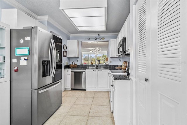 kitchen with dark stone countertops, crown molding, white cabinetry, sink, and appliances with stainless steel finishes