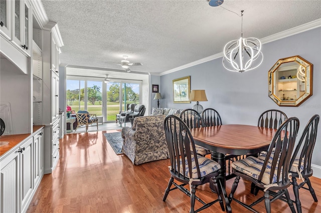 dining room featuring ceiling fan with notable chandelier, crown molding, wood-type flooring, and a textured ceiling