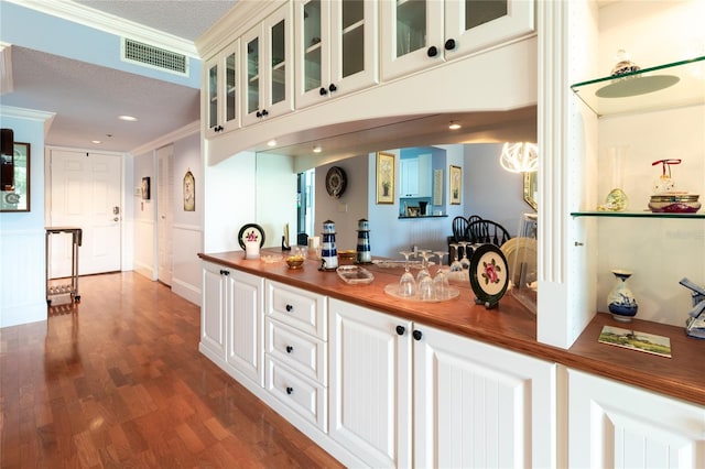 kitchen featuring a textured ceiling, crown molding, butcher block counters, and wood-type flooring