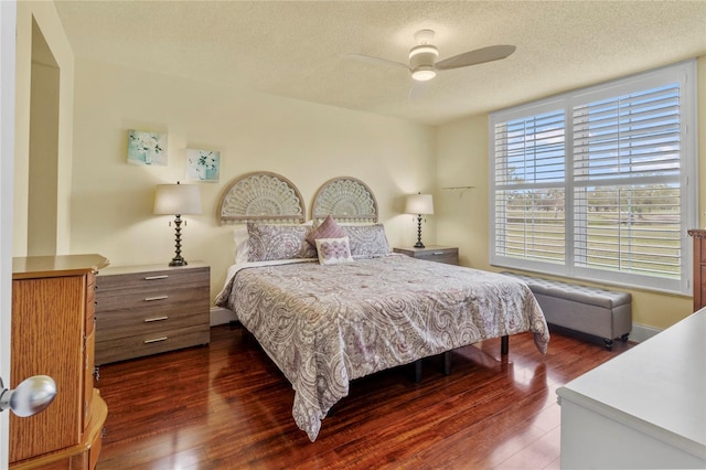 bedroom with a textured ceiling, ceiling fan, and dark hardwood / wood-style floors