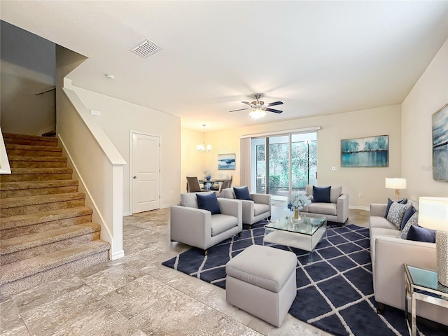 living room featuring baseboards, stairs, visible vents, and ceiling fan with notable chandelier