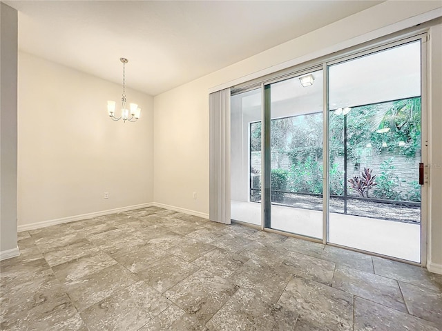 empty room with a notable chandelier, stone finish flooring, and baseboards