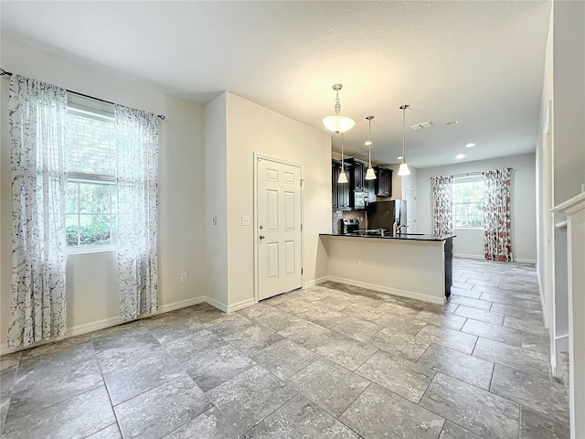 kitchen with stainless steel appliances, kitchen peninsula, decorative light fixtures, and sink