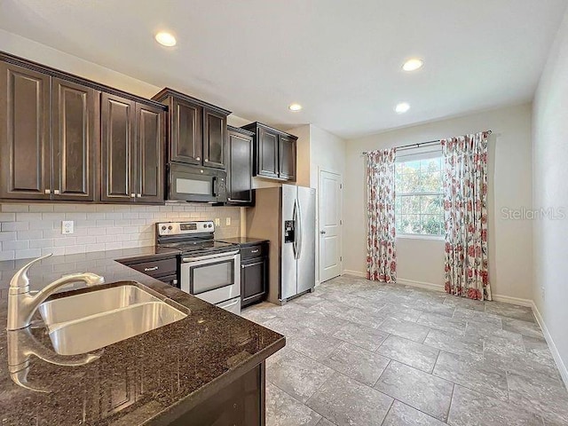 kitchen featuring decorative backsplash, stainless steel appliances, dark brown cabinets, dark stone counters, and sink