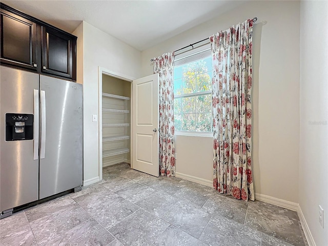 unfurnished dining area featuring baseboards and stone finish flooring