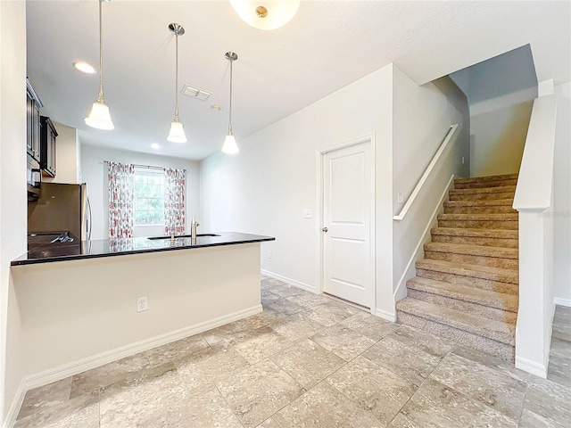 kitchen with freestanding refrigerator, visible vents, baseboards, dark countertops, and decorative light fixtures