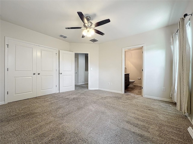 unfurnished bedroom featuring a closet, ensuite bath, ceiling fan, and carpet floors