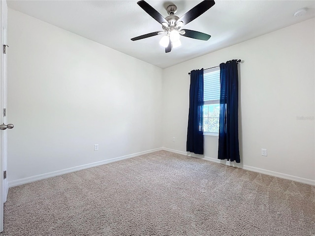 empty room with light colored carpet, baseboards, and a ceiling fan