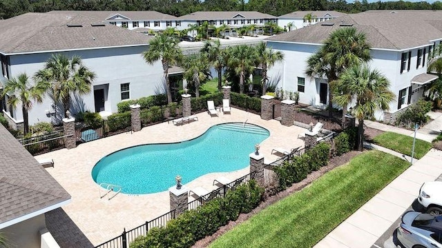 pool with fence, a patio area, and a residential view