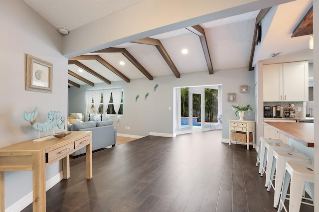 kitchen featuring a textured ceiling, dark hardwood / wood-style flooring, backsplash, lofted ceiling with beams, and white cabinets