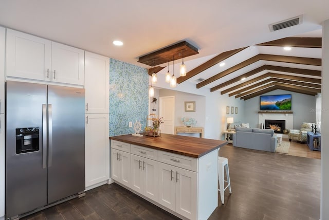 kitchen featuring stainless steel fridge with ice dispenser, lofted ceiling with beams, butcher block counters, and white cabinets