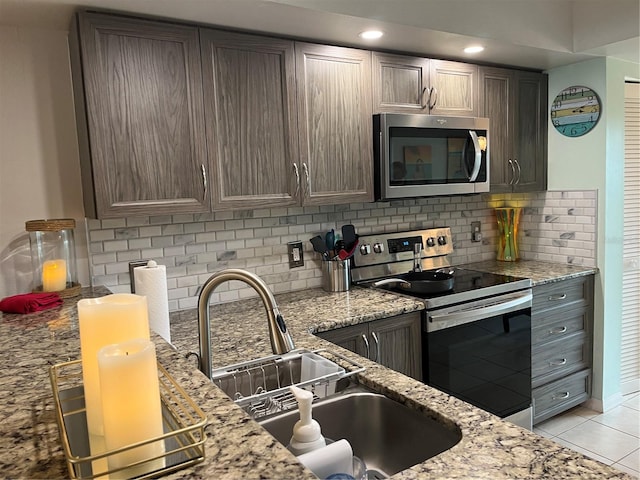 kitchen with decorative backsplash, light tile patterned floors, light stone counters, and appliances with stainless steel finishes