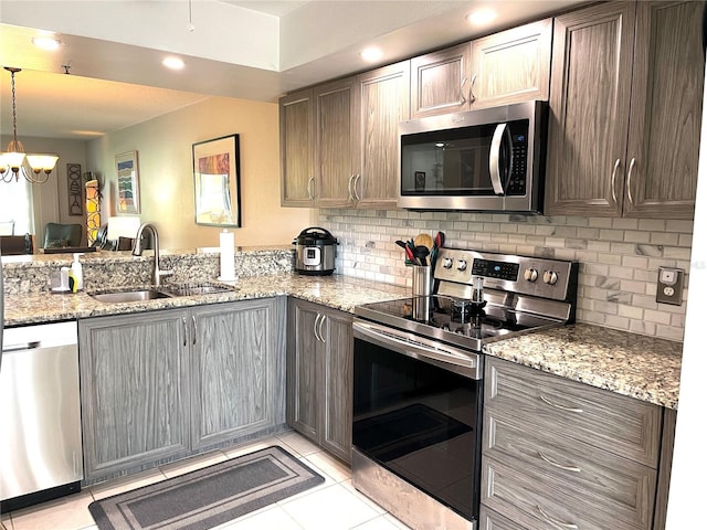 kitchen featuring light stone countertops, light tile patterned flooring, a sink, decorative backsplash, and stainless steel appliances