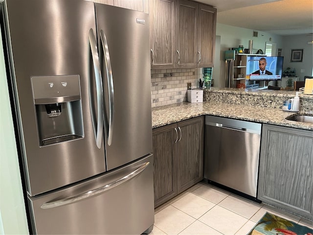 kitchen with light tile patterned floors, stainless steel appliances, light stone counters, and tasteful backsplash