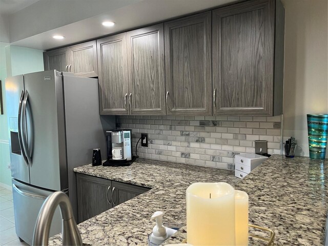 kitchen featuring tasteful backsplash, recessed lighting, stainless steel fridge with ice dispenser, and light stone countertops