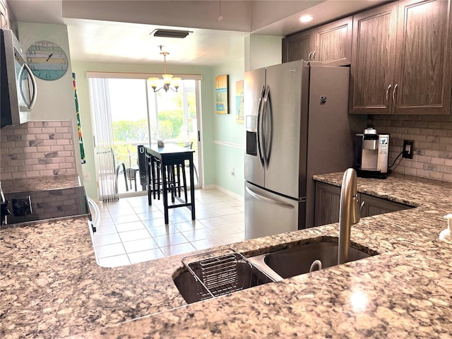 kitchen with light tile patterned floors, light stone countertops, visible vents, stainless steel appliances, and backsplash