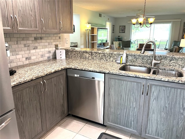 kitchen with a sink, light stone counters, tasteful backsplash, light tile patterned floors, and dishwasher