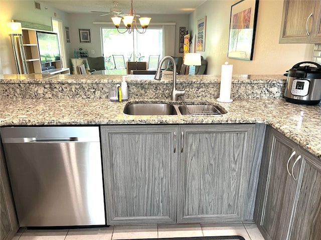 kitchen with dishwasher, light stone countertops, gray cabinets, and a sink