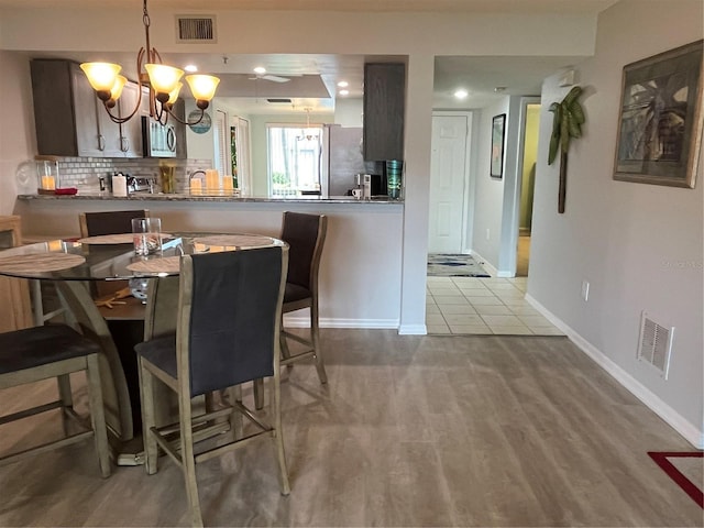 dining area with visible vents, wood finished floors, baseboards, and a chandelier