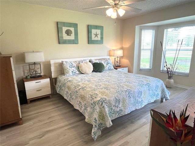 bedroom featuring ceiling fan, light wood-style floors, baseboards, and a textured ceiling