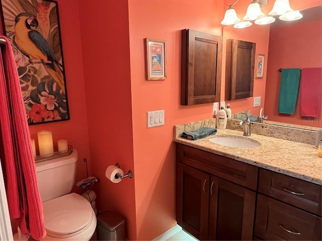 bathroom featuring vanity, an inviting chandelier, and toilet