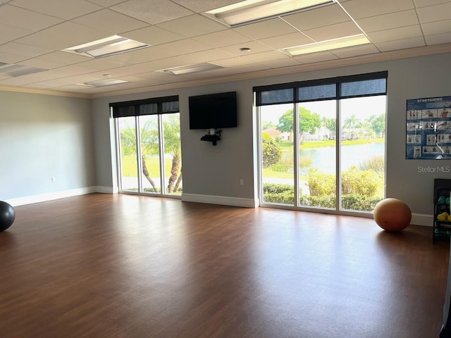 exercise room with a drop ceiling, crown molding, baseboards, and wood finished floors