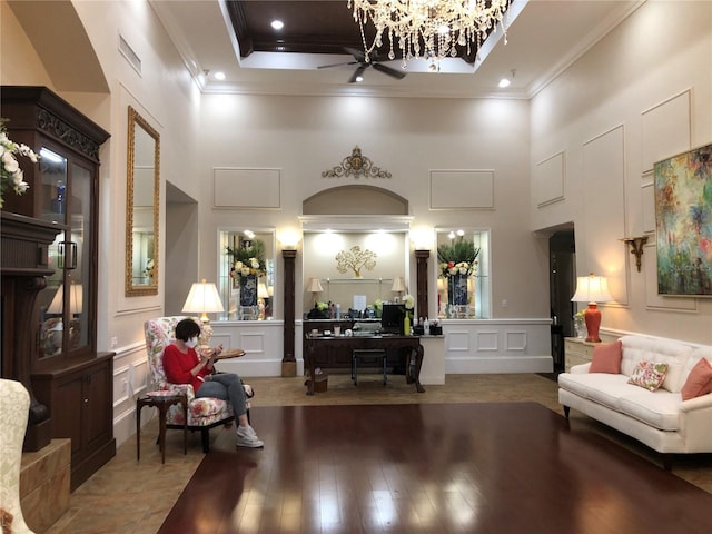 interior space featuring a decorative wall, a high ceiling, ceiling fan, and ornamental molding