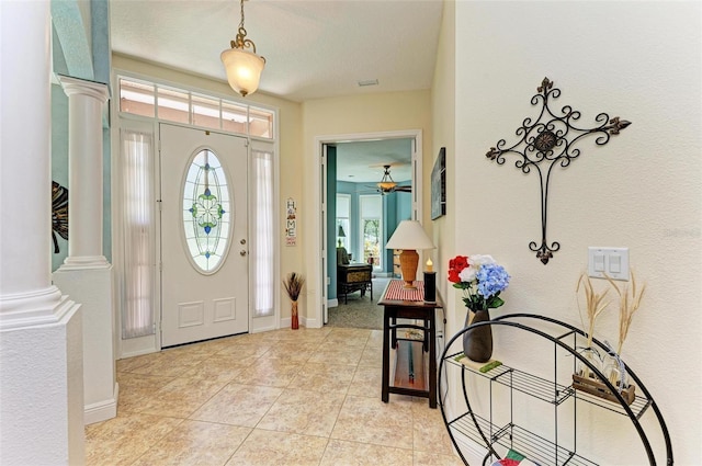 tiled entrance foyer with a textured ceiling, ceiling fan, and ornate columns