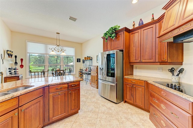 kitchen featuring custom range hood, light stone counters, decorative light fixtures, and stainless steel fridge with ice dispenser