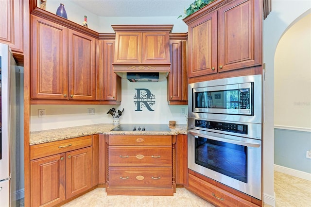 kitchen featuring light tile patterned floors, custom range hood, light stone countertops, and appliances with stainless steel finishes