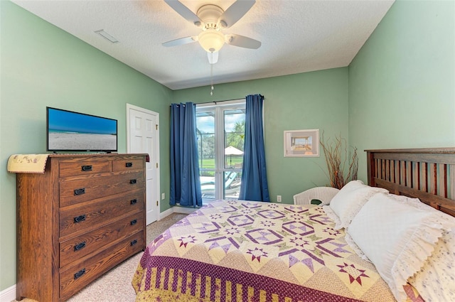 carpeted bedroom with a textured ceiling, access to exterior, and ceiling fan