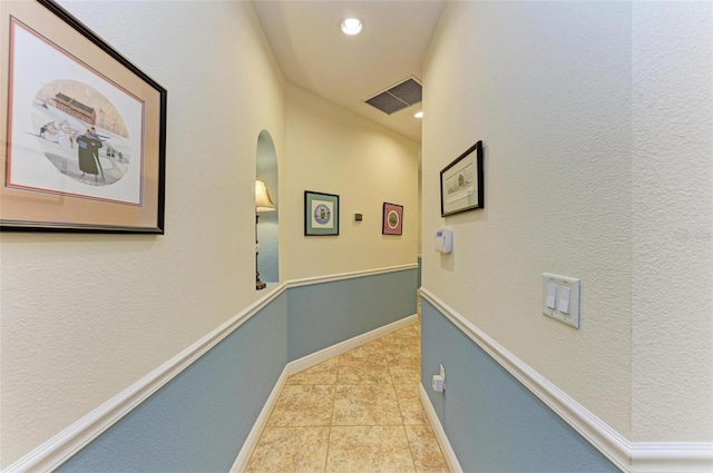 hallway featuring vaulted ceiling and light tile patterned floors