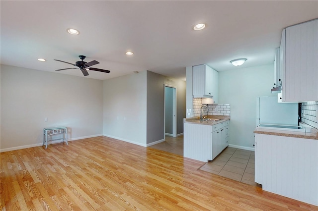 kitchen with ceiling fan, white cabinets, light hardwood / wood-style flooring, and sink