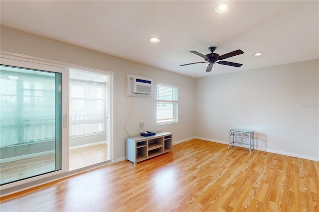 empty room featuring light wood-type flooring, ceiling fan, and a wall mounted air conditioner