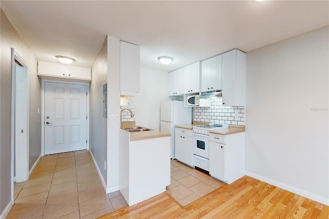 kitchen with sink, white appliances, light hardwood / wood-style flooring, backsplash, and white cabinetry