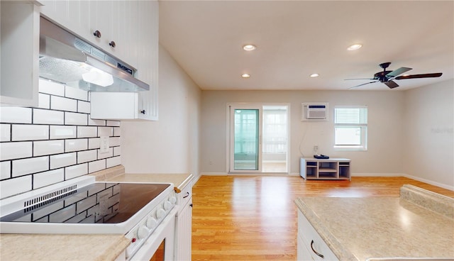 kitchen featuring ceiling fan, white cabinets, stove, tasteful backsplash, and light wood-type flooring