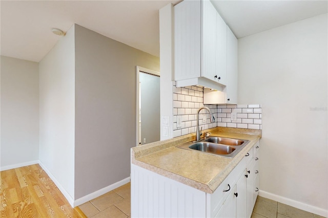 kitchen featuring light hardwood / wood-style floors, sink, tasteful backsplash, and white cabinetry