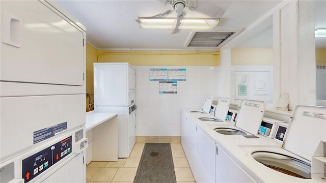 clothes washing area featuring stacked washer / drying machine, tile walls, washing machine and dryer, and light tile patterned flooring